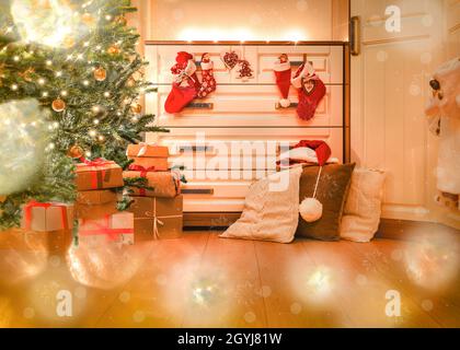 Hell dekoriertes Zimmer zu Weihnachten. Geschenke unter dem Weihnachtsbaum und in den Stiefeln des Weihnachtsmanns. Stockfoto