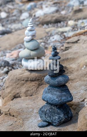Zwei Steinhaufen, die am Strand Kunstwerke bilden, Steine oder Felsen, die übereinander platziert sind. Stockfoto