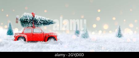 Deformierte und nicht erkennbare Auto trägt Einen Weihnachtsbaum in Snowy Landscape Stockfoto