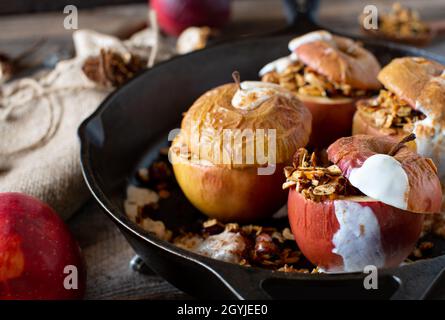 Hausgemachtes Frühstückszerealien mit frisch gebackenen Äpfeln und Müsli mit Zimt und Joghurt. Serviert auf rustikalem Holztisch. Stockfoto