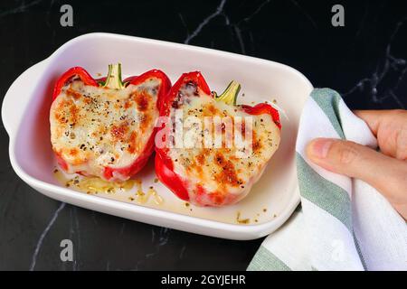 Hand halten eine Schüssel mit frisch gekochten gefüllten Paprika mit Geschirrtuch Stockfoto