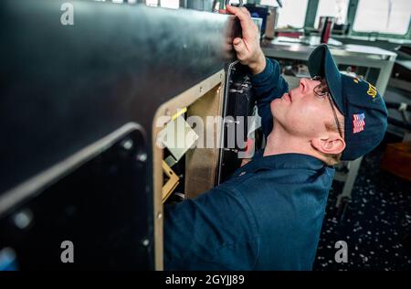 SEA OF JAPAN (JAN 6, 2020) Elektroniktechniker der 1. Klasse Anthony Deluca aus Philadelphia greift in die Rückseite der Steuerkonsole des Schiffes, um das Steuerruder auf der Brücke des Arleigh Burke-Klasse Lenkraketen-Zerstörers USS Milius (DDG 69) zu trennen. Milius führt derzeit Operationen in der Region Indo-Pazifik durch, während er an Destroyer Squadron (DESRON) 15, die größte vorwärtseingesetzte DESRON der Marine und die wichtigste Surface Force der 7. US-Flotte, übertragen wurde. (USA Navy Foto von Mass Communication Specialist 2nd Class Taylor DiMartino) Stockfoto