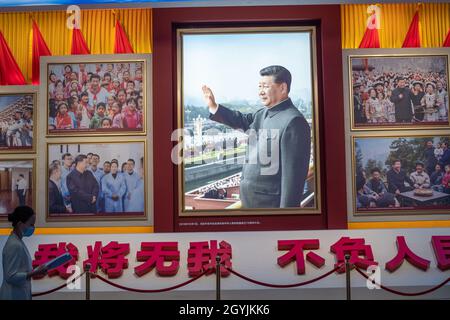 Eine Dame geht an Bildern vorbei, die den chinesischen Präsidenten Xi Jinping im Museum der Kommunistischen Partei Chinas in Peking zeigen. 08-Okt-2021 Stockfoto