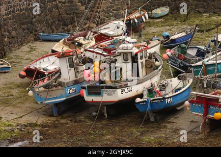 Kleine Fischerboote wurden im Gezeitenhafen in Cornwall, England, festgebunden und ausgetrocknet Stockfoto