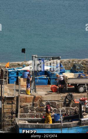 Am Ende des Tages können Sie nach einem kleinen Fischerboot fischen, während die Familie beim Entladen des Fänge mithilft Stockfoto
