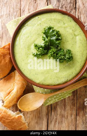 Cremige Kartoffel-Kale-Suppe, serviert mit Brot aus der Nähe in einer Schüssel auf dem Tisch. Vertikale Draufsicht von oben Stockfoto