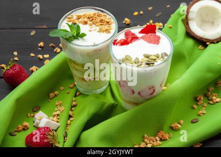 Hausgemachter Joghurt mit Müsli, Obst und Kokosnuss, Blick von oben auf Holzhintergrund Stockfoto