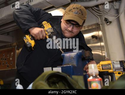 200113-N-DE082-192 YOKOSUKA, Japan (Jan 13, 2020) - Rumpftechniker der Seemann Jakob Duran aus Caldwell, Idaho, bohrt ein Loch, während er im Rumpftechniker-Laden an Bord des US-Flaggschiffs USS Blue Ridge (LCC 19) eine Sicherheitshalterung für die See fertigt. Blue Ridge ist das älteste operationelle Schiff der Marine und arbeitet als Kommandoschiff der 7. Flotte aktiv an der Förderung von Beziehungen zu Verbündeten und Partnern in der Indo-Pazifik-Region. (USA Navy Foto von Mass Communication Specialist Seaman Sarah Eaton) Stockfoto