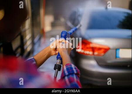 Frau mit Hochdruckwasserkanone, Autowäsche Stockfoto