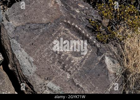 Eine anthropomorphe Figur, die auf einem Basaltsteinblock in der Petroglyph-Stätte Three Flueans, New Mexico, geschnitzt wurde. Stockfoto