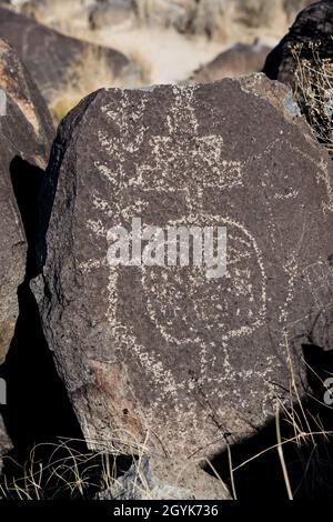 Ein menschliches Gesicht, das auf einem Basaltsteinbrocken in der Petroglyph-Stätte Three-Flues, New Mexico, geschnitzt wurde. Stockfoto