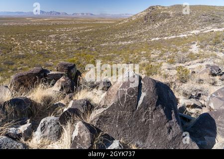 Anthropomorphe Figuren, die auf einem Basaltsteinblock in der Petroglyph-Stätte Three-Flues, New Mexico, geschnitzt wurden. Stockfoto