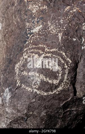 Ein menschliches Gesicht, das auf einem Basaltsteinbrocken in der Petroglyph-Stätte Three-Flues, New Mexico, geschnitzt wurde. Stockfoto