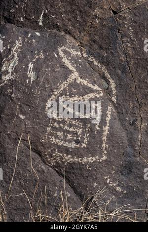 Eine anthropomorphe Figur, die auf einem Basaltsteinblock in der Petroglyph-Stätte Three Flueans, New Mexico, geschnitzt wurde. Stockfoto