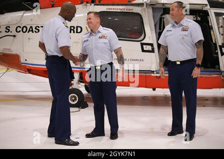 Bef. Marcus Canady, Kommandant der Air Station Houston, schüttelt sich die Hände mit dem Kleinoffizier 3rd Class James Chandler während einer Preisverleihung, um Chandler für seine Handlungen während des Tropensturms Imelda an der Air Station Houston, 15. Januar 2020, zu würdigen. Chandler wurde mit der „Coast Guard Commendation Medal“ ausgezeichnet, weil er eine über eine Stunde lang kontinuierlich CPR an einem geretteten Patienten durchgeführt hat, während er auf medizinische Notdienste wartete. (USA Foto der Küstenwache von Paige Hause der 3. Klasse) Stockfoto