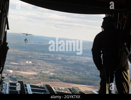 Master-Sgt. Khaleef Graham, 118. Airlift Squadron Ladermeister, beobachtet, wie ein C-130H Hercules, der dem 103. Luftlift-Flügel zugewiesen wurde, eine schwere Palette über die Fallzone auf der Westover Air Reserve Base, Chicopee, Mass., 15. Januar 2020 fallen lässt. Die Flugzeugbesatzungen der 103. Flogen eine zwei-Schiffe-Formation und führten Luftabwürfe mit schweren Paletten und Containerliefersystemen durch, um die wichtigsten taktischen Luftlift-Fähigkeiten zu trainieren. (USA Foto der Air National Guard von Staff Sgt. Steven Tucker) Stockfoto