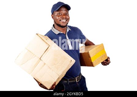 Junger Mann, der in einem Hut auf weißem Hintergrund stand und Pappkartons mit einem Lächeln trug. Stockfoto