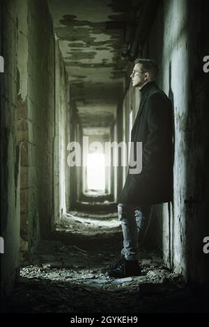 Junger Mann mit Brillen in dunkel ruinierten Korridor vertikal Stockfoto