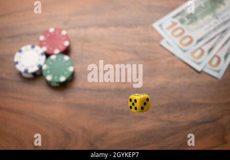Gelbe Würfel, Spielgeld und Chip im Hintergrund. Stockfoto