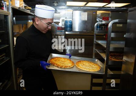 200118-N-ZI768-1002 NEWPORT NEWS, VA. (Jan 18, 2020) kulinarische Spezialistin Seaman Lehrling Isaac Rodriguez, der an Bord des Flugzeugträgers USS George Washington (CVN 73) der Nimitz-Klasse für das allgemeine Chaos eingesetzt wurde, holt Pizzen von einem Kühlregal in der Kombüse an Bord der schwimmenden Unterkunftseinrichtung. George Washington wird derzeit in der Newport News Shipyard einer Überholung des Tankkomplexes (RCOH) unterzogen. Bei RCOH handelt es sich um ein fast vierjähriges Projekt, das nur einmal während der 50-jährigen Lebensdauer eines Trägers durchgeführt wird. Dazu gehören die Betankung der beiden Kernreaktoren des Schiffes sowie umfangreiche Reparaturen, Upgrades und Modernisierungen Stockfoto