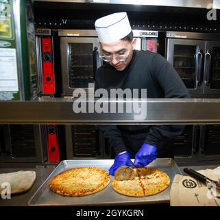 200118-N-ZI768-1006 NEWPORT NEWS, VA. (Jan 18, 2020) kulinarische Spezialistin Seaman Lehrling Isaac Rodriguez, der dem allgemeinen Chaos an Bord des Flugzeugträgers USS George Washington (CVN 73) der Nimitz-Klasse zugeteilt wurde, schneidet Pizza in der Kombüse an Bord der schwimmenden Unterkunft. George Washington wird derzeit in der Newport News Shipyard einer Überholung des Tankkomplexes (RCOH) unterzogen. Bei RCOH handelt es sich um ein fast vierjähriges Projekt, das nur einmal während der 50-jährigen Lebensdauer eines Trägers durchgeführt wird. Dazu gehören die Betankung der beiden Kernreaktoren des Schiffes sowie umfangreiche Reparaturen, Upgrades und Modernisierungen. (USA Navy Pho Stockfoto