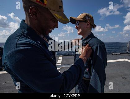 GOLF VON OMAN (JAN 22, 2020) - Bef. Christopher Carroll, kommandierender Offizier des Lenkraketen-Zerstörers USS Carney (DDG 64), pinnt Ensign Anne Fisher mit ihrem Surface Warfare Officer Warfare Device, 22. Januar 2020. Carney wird in den Einsatzbereich der 5. US-Flotte eingesetzt, um Marineinteraktionen zu unterstützen, um die maritime Stabilität und Sicherheit in der Zentralregion zu gewährleisten und das Mittelmeer und den Pazifik durch den westlichen Indischen Ozean und drei strategische Engpässe zu verbinden. (USA Navy Foto von Mass Communication Specialist 1st Class Fred Gray IV) Stockfoto