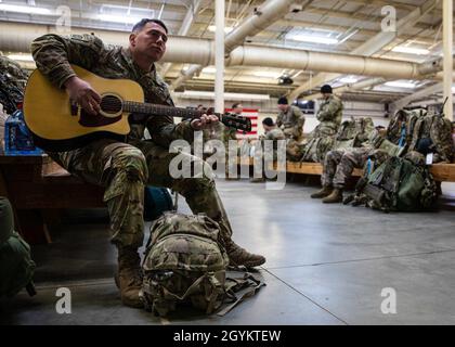 Ein Fallschirmjäger, der dem 1. Bataillon, dem 325. Airborne Infanterie-Regiment, dem 2. Brigade-Kampfteam, der 82. Airborne-Division zugewiesen ist, spielt Gitarre an der Green Ramp, während er auf einen Flug nach Kolumbien am 23. Januar 2020 in Fort Bragg, N.C. wartet Diese Fallschirmjäger gehen nach Kolumbien, um gemeinsam mit ihren kolumbianischen Partnern an einer dynamischen Machtübung teilzunehmen. Stockfoto