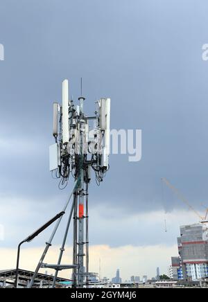 Antennenmast für drahtlose Kommunikation, Antennenmast für Mobiltelefone auf dem Dach eines baufälligen Gebäudes Stockfoto