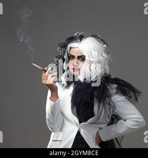 Eine tödliche Schönheit in einem gewagten Modebild mit schwarzen und weißen Haaren. Ein rebellisches stylisches Bild für Halloween. Eine junge Frau in einem schwarz-weißen Outfi Stockfoto