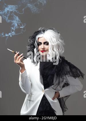 Eine tödliche Schönheit in einem gewagten Modebild mit schwarzen und weißen Haaren. Ein rebellisches stylisches Bild für Halloween. Eine junge Frau in einem schwarz-weißen Outfi Stockfoto