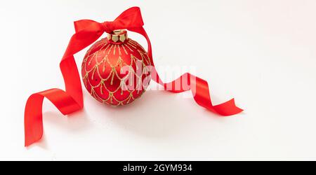 Weihnachtskugel mit goldenem Glitzer und gebundener roter Schleife. Traditionelle Feiertagsschmuck isoliert auf weißem Hintergrund. Frohes neues Jahr und Merry Stockfoto