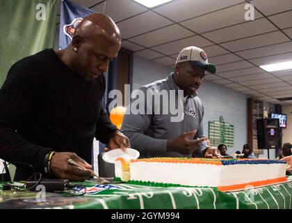 TOLLE SEEN, Il. (Jan 29, 2020) Donald Driver (links), ehemaliger Spieler der Green Bay Packers, und Alex Brown, ehemaliger Spieler der Chicago Cubs, schnitten und servieren einen Kuchen während eines Super Bowl Essens in der Galley 535 auf der Naval Station Great Lakes. Die Veranstaltung, die von der Great Lakes Moral, Welfare, and Recreation (MWR) veranstaltet wurde, hatte Essen im Heckklappenstil, ein Treffen mit den Spielern und eine Tombola für die Matrosen. (USA Navy Foto von Mass Communication Specialist 2nd Class Brigitte Johnston) Stockfoto