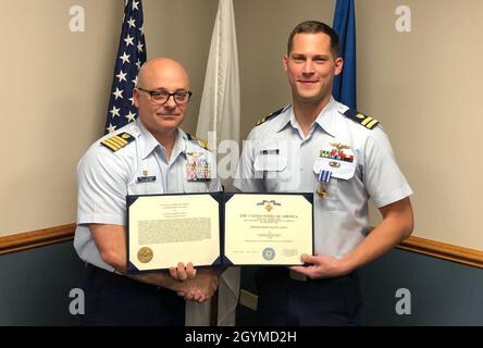 Capt. William Sasser, der Kommandant des Aviation Training Center Mobile, Alabama, überreicht LT. Gregory Bukata ein herausragendes Flying Cross für seine Handlungen während des Hurrikans Harvey in Mobile am 31. Januar 2020. Das Distinguished Flying Cross ist Amerikas ältester Preis für die militärische Luftfahrt. (USA Foto der Küstenwache/Veröffentlichung) Stockfoto