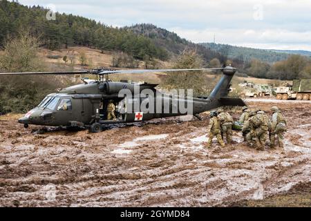 US Army Sgt. Chelsey Pcolar, Charlie Company, 2nd Bataillon, 3rd Combat Aviation Brigade, 3rd Infantry Division schaufelt durch knietiefen Schlamm und führt ein Liter-Team zu ihrem wartenden HH-60M MEDEVAC Blackhawk Hubschrauber während des Combined Resolve XIII, 31. Januar 2020, im Hohenfels Trainingsgebiet. (USA Armeefoto von Sgt. 1. Klasse Garrick W. Morgenweck) Stockfoto