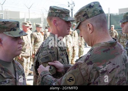 Brig. General Howard Geck, kommandierender General, 103. Expeditionary Sustainment Command (ESC), überreicht Kapitän Daniel Biegger, 103. ESC, während einer Preisverleihung, Patching und Promotion im Camp Arifjan, Kuwait, am 2. Februar 2020, einen Kampfpatch. (USA Army Reserve Foto von SPC. Dakota Vanidestine) Stockfoto