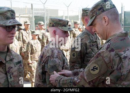 Brig. General Howard Geck, kommandierender General, 103. Expeditionary Sustainment Command (ESC), überreicht Capt. Seth Johnson, 103. ESC, während einer Preisverleihung, Patching und Promotion im Camp Arifjan, Kuwait, am 2. Februar 2020, einen Kampfpatch. (USA Army Reserve Foto von SPC. Dakota Vanidestine) Stockfoto