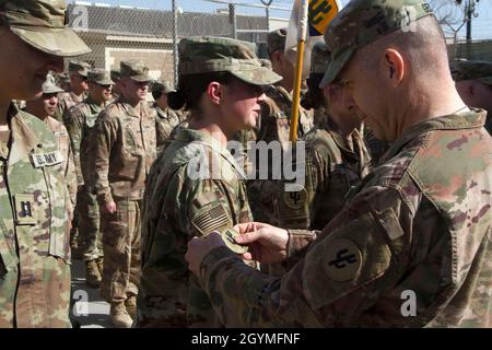 Brig. General Howard Geck, kommandierender General, 103. Expeditionary Sustainment Command (ESC), stellt SPC vor. Brittany Engels, 103. ESC, mit einem Kampfpatch während einer Preisverleihung, Patchen und Promotion im Camp Arifjan, Kuwait, 2. Februar 2020. (USA Army Reserve Foto von SPC. Dakota Vanidestine) Stockfoto