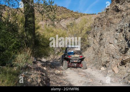 Auf dem Dripping Springs Trail in den Plomosa Mountains in der Nähe von Quartzsite, Arizona, folgt man einem Geländewagen mit Allradantrieb UTV. Stockfoto