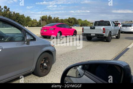 Palo Alto, Kalifornien, USA. Oktober 2021. Auf dem Highway 101 in Palo Alto wird ein rosafarbener Tesla im Verkehr gefahren. Elon Musk, CEO von Tesla, sagte, dass das Unternehmen seinen Hauptsitz von Palo Alto, Kalifornien, nach Austin, Texas, verlagern würde. (Bild: © K.C. Alfred/ZUMA-Pressdraht) Stockfoto