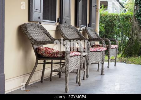 Drei Korbstühle sitzen auf der Veranda. Sie sind ein Stuhl im Retro-Stil. Stockfoto