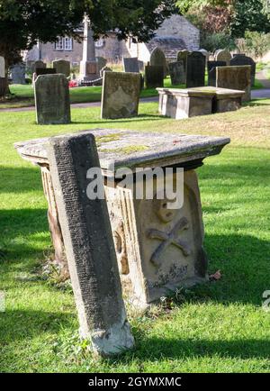 Ein ungewöhnlicher früher Grabstein, der im Pestdorf Eyam, Derbyshire, mit einem Totenkopf- und Kreuzknochenbild geschnitzt wurde. Stockfoto