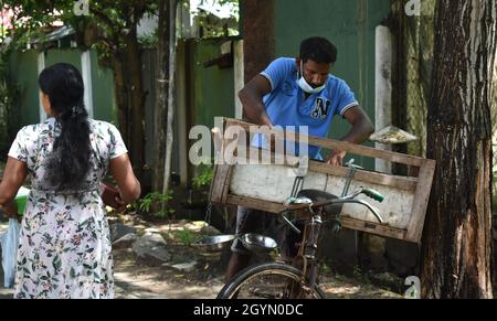 Eine Frau, die Fisch von einem Händler kauft, der Fisch und Meeresfrüchte auf seinem Fahrrad verkauft, indem er täglich von Haus zu Haus geht. Colombo, Sri Lanka. Stockfoto