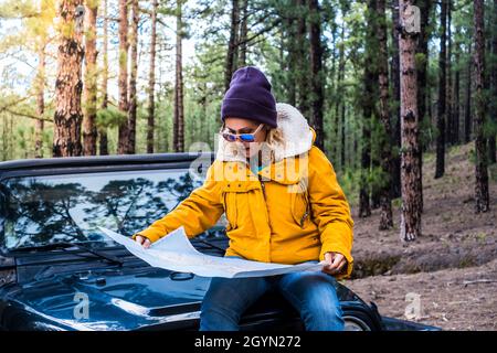 Junge Frau setzt sich auf das Auto und überprüfen Sie den Kartenführer in Alone travel Adventure Lifestyle - weibliche Menschen genießen Wald und Natur Wald fahren das Auto Stockfoto
