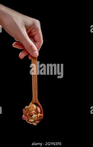 Holzlöffel mit Erdnussbutter und Erdnüssen auf schwarzem Hintergrund. Stockfoto