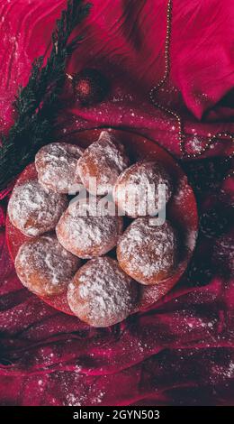 Vertikale Aufnahme eines Bündels von Donuts auf einer roten Platte, die mit Zuckerpulver bedeckt ist Stockfoto