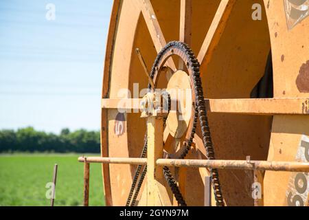 Nahaufnahme des Kettenantriebs am orangefarbenen Metallrad. Stockfoto