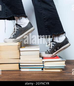 Ein Mädchen klettert eine Leiter, die aus einigen Bücherstapeln besteht Stockfoto