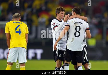 Hamburg, Deutschland. Okt. 2021. Fußball: WM-Qualifikation Europa, Deutschland - Rumänien, Gruppenphase, Gruppe J, Matchday 7 im Volksparkstadion. Der Deutsche Thomas Müller (M) umarmt Leon Goretzka nach dem Spiel. Auf der linken Seite reagiert der Rumäne Cristian Manea nach dem Spiel mit Enttäuschung. Kredit: Marcus Brandt/dpa/Alamy Live Nachrichten Stockfoto