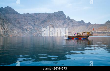 Musandam, Oman - 04.01.2018: Menschen auf einem traditionellen arabischen Dhow-Boot, das in den Fjorden von Musandam, Oman, segelt. Trüber Frühlingstag auf Arabisch Stockfoto