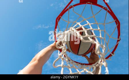 Mann dunking Basketball durch Netzring mit Händen, Sport Stockfoto